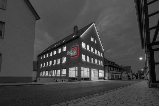 Das FOCUS-Haus in der Kulmbacher Straße 8 in Burgkunstadt am Abend, Fassade mit leuchtendem FOCUS-Zeichen, Schwarz-Weiß